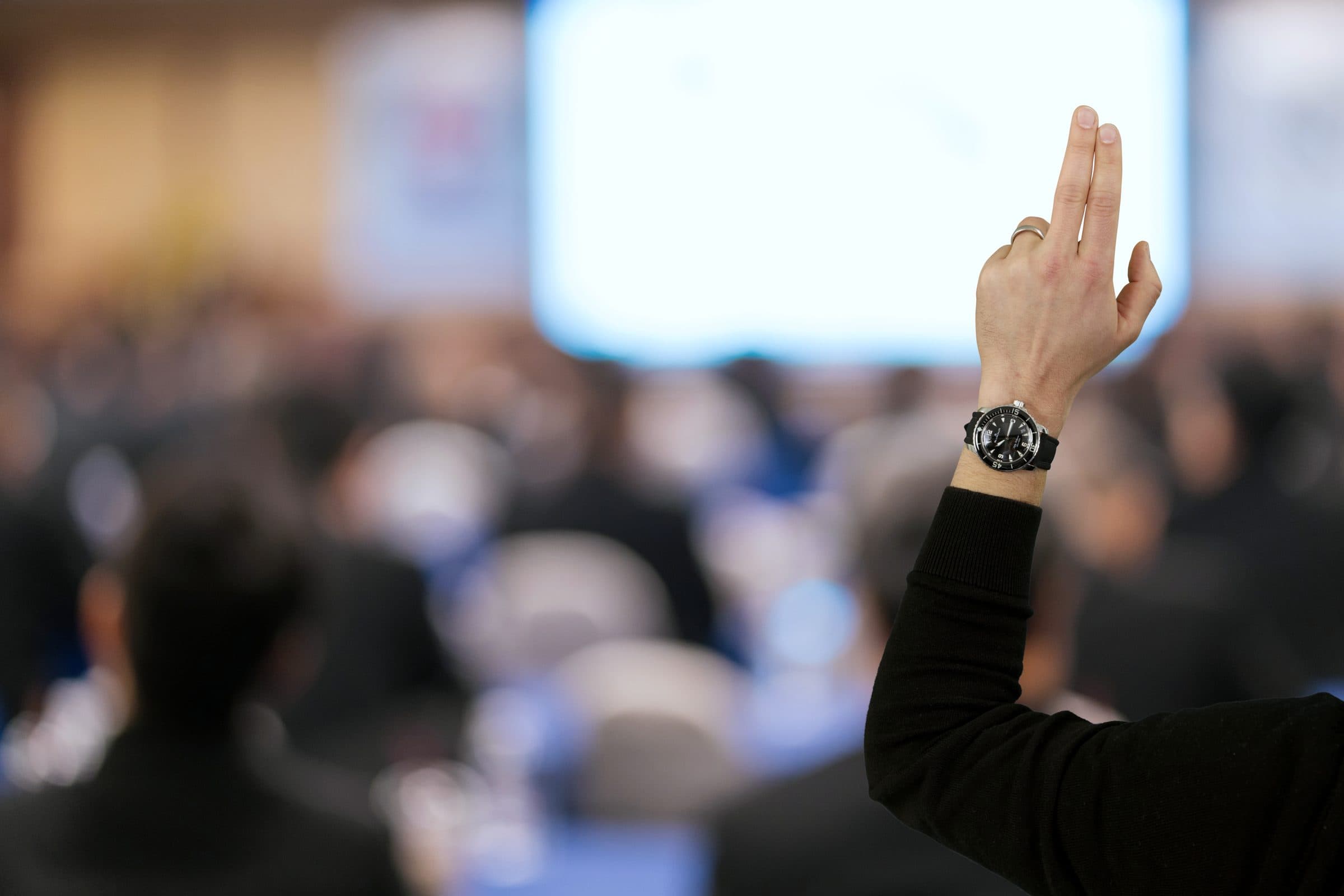 Erhobene Hand mit Uhr im Auktionssaal